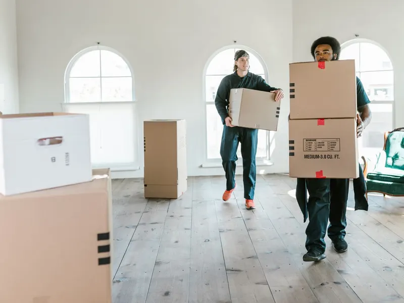 Umzugsteam trägt Umzugskartons durch eine helle Wohnung